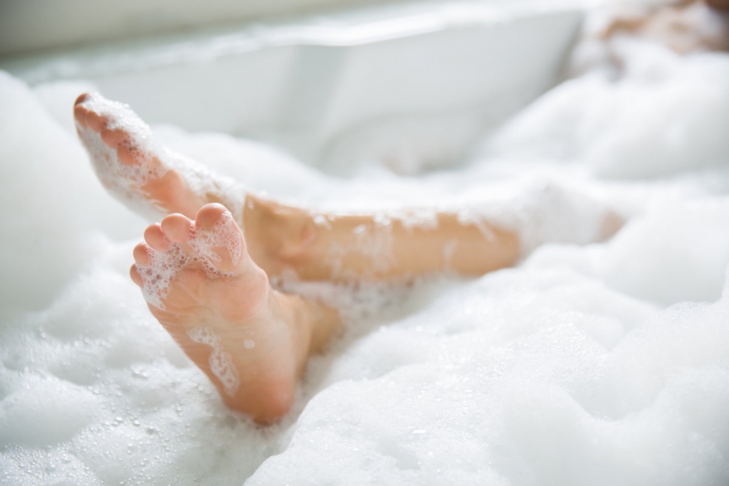 woman's feet in bathtub having bubble bath